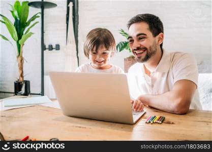 Little boy and his father using a laptop together while staying at home. New normal lifestyle. Monoparental concept.