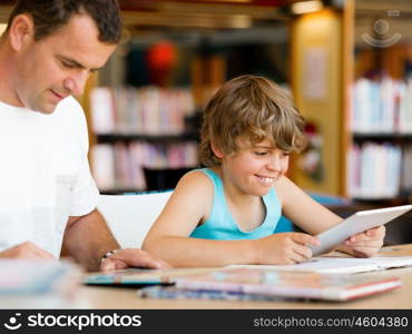 Little boy and his father with computer in library. Little boy and his father with laptop