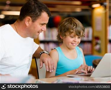 Little boy and his father with laptop in library. Little boy and his father with laptop