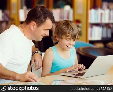 Little boy and his father with laptop in library. Little boy and his father with laptop