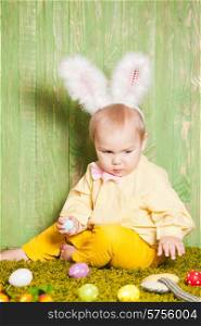 Little boy as a Easter rabbit on the grass is hunting for colorful eggs. Easter rabbit toddler