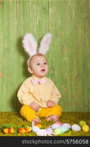 Little boy as a Easter rabbit on the grass with colorful eggs. Easter rabbit toddler