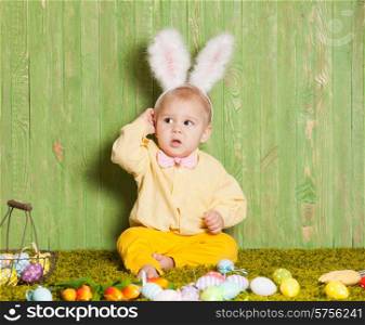 Little boy as a Easter rabbit on the grass with colorful eggs. Easter rabbit toddler