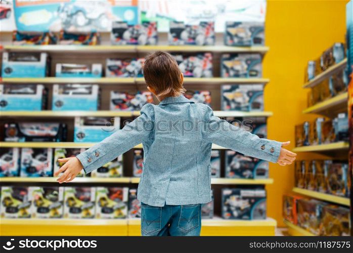Little boy at the shelf in kids store, back view. Son choosing toys in supermarket, family shopping. Little boy at the shelf in kids store, back view