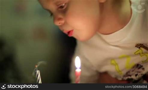 Little boy blowing out two candles on his birthday cake, everybody applauding, then mother taking away the candles.