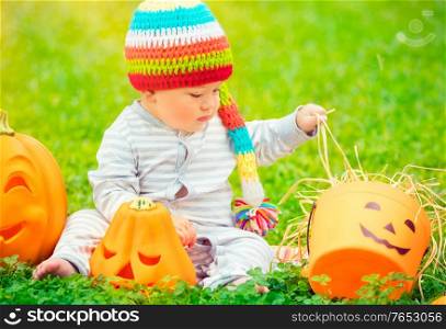 Little boy celebrates Halloween holiday, enjoying beautiful traditional festive decoration outdoors in warm sunny day, happy american holiday