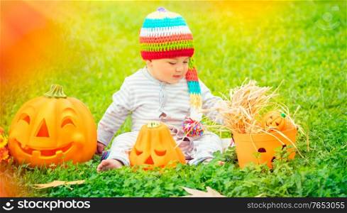 Little boy celebrating Halloween holiday, enjoying beautiful traditional festive decoration outdoors in warm sunny day, happy american holiday