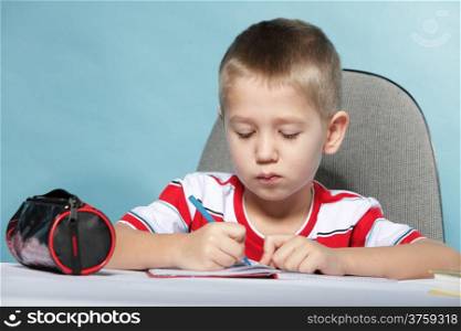 little boy child kid drawing with color pencils on blue background