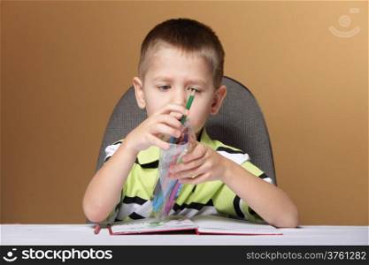 little boy child kid drawing with color pencils on brown background