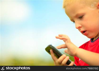 Little boy child kid playing games on smartphone mobile phone outdoor. Technology generation.