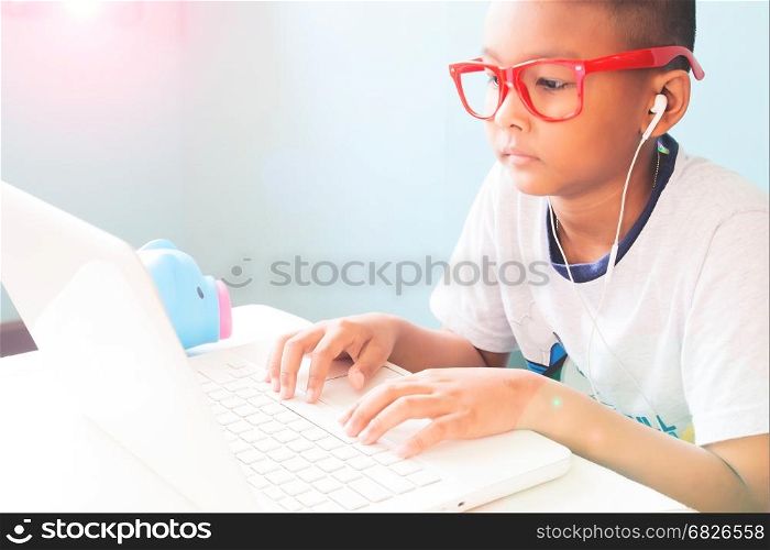 Little boy child wearing red glasses listening and using laptop computer