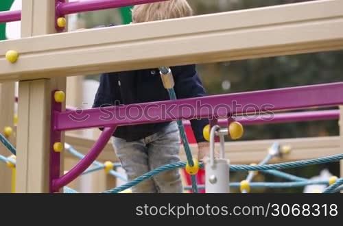 Little boy climbing playground equipment. Outdoor activity for children.