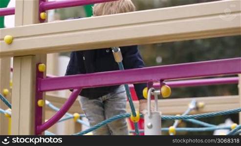 Little boy climbing playground equipment. Outdoor activity for children.