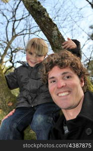 Little boy climbing tree with father