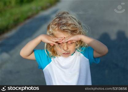 Little boy covering his eyes by the sun, on a sunny day