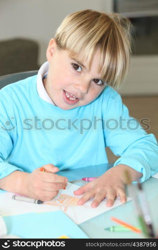 little boy drawing at school with wax crayons