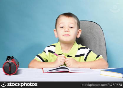 little boy drawing with color pencils on blue background