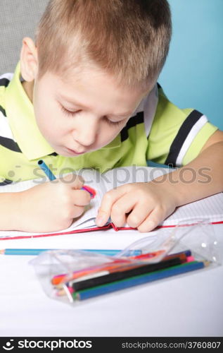 little boy drawing with color pencils on blue background