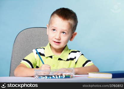 little boy drawing with color pencils on blue background