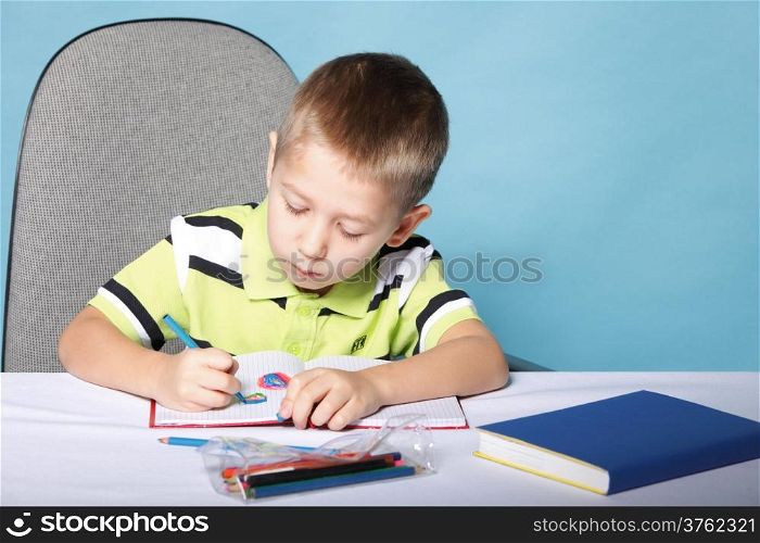 little boy drawing with color pencils on blue background