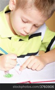 little boy drawing with color pencils on orange background