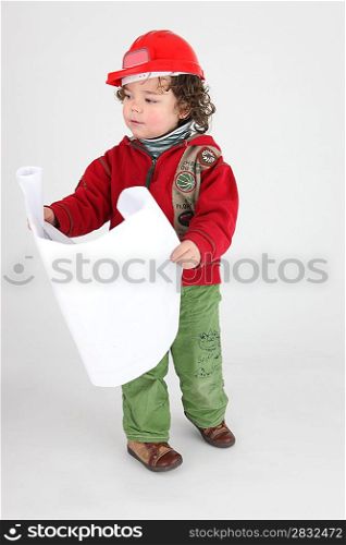 Little boy dressed as builder holding plans