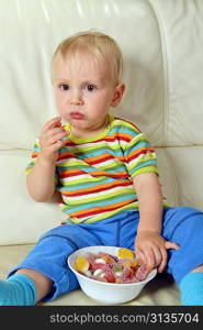 Little boy eating sweets. full bowl of candy