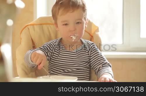 Little boy eats porridge in the morning.