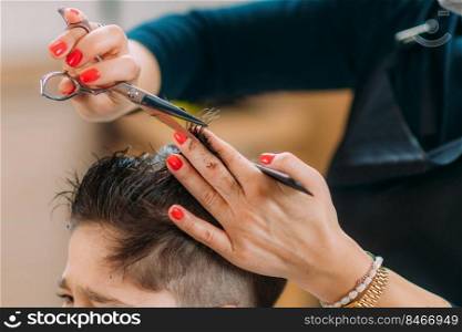 Little boy getting his hair cut by a female hairdresser in a hair salon for children.. Hairdresser Cutting Boy’s Hair