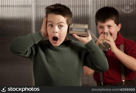 Little boy getting shocking message from friend on tin can phone