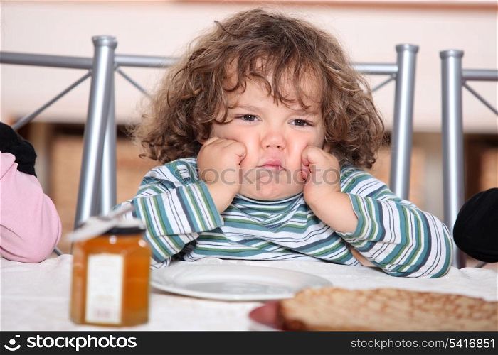 little boy grouching in front a plate of crepes