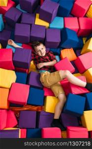 Little boy having fun with soft colorful cubes in childrens entertainment center. Happy childhood. Little boy having fun with soft colorful cubes