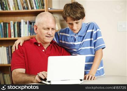 Little boy helping his middle-aged father use the computer.