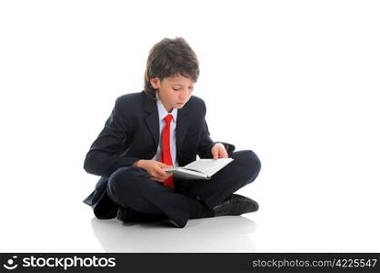 little boy in a business suit reading a book sitting on the floor. Isolated on white background