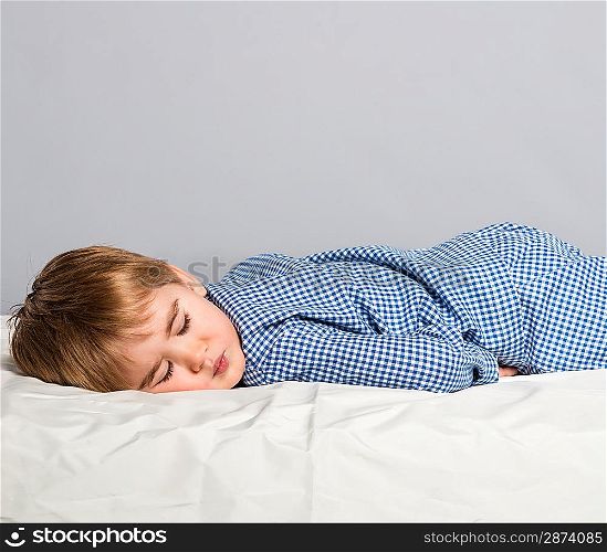 Little boy in blue pyjamas sleeping in bed