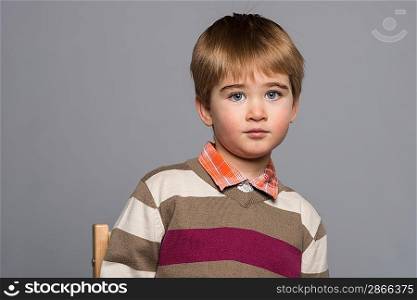 Little boy in cardigan sitting on chair