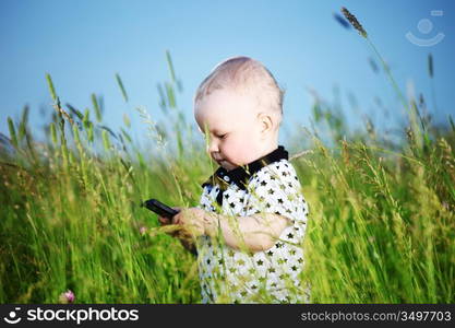 little boy in green grass call by phone