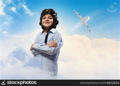 Little boy in pilot&rsquo;s hat. Image of little boy in pilots helmet with flying airplane in background