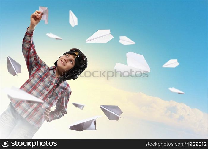 Little boy in pilot&rsquo;s hat. Image of little boy in pilots helmet playing with paper airplane