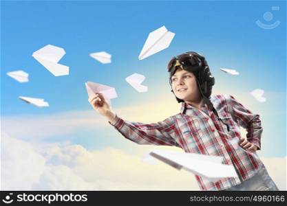 Little boy in pilot&rsquo;s hat. Image of little boy in pilots helmet playing with paper airplane