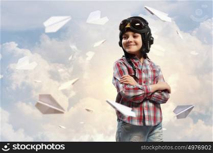 Little boy in pilot&rsquo;s hat. Image of little boy in pilots helmet with paper airplanes in background