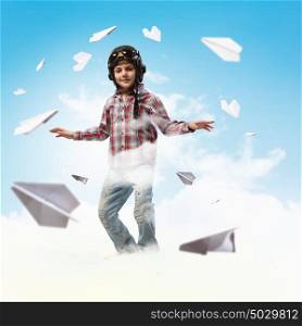 Little boy in pilot&rsquo;s hat. Image of little boy in pilots helmet with paper airplanes in background