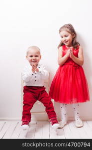 Little boy in red pants and a girl in a red dress posing for photos in harmony