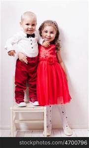 Little boy in red pants and a girl in a red dress posing for photos in harmony