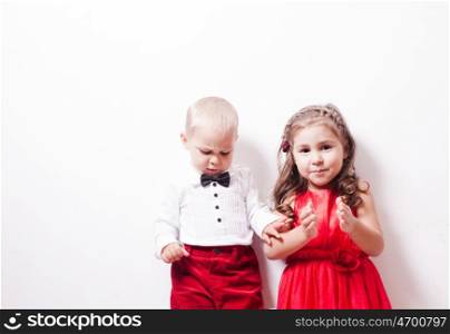 Little boy in red pants and a girl in a red dress posing for photos in harmony