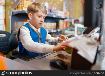 Little boy in uniform at the register playing salesman, playroom. Kids plays sellers in imaginary supermarket, sales profession learning. Boy in uniform at the register playing salesman