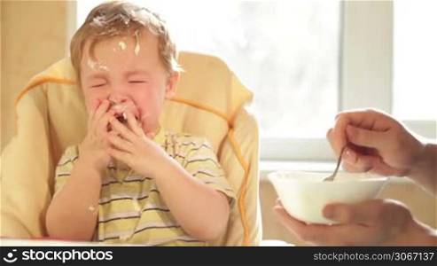 Little boy is crying because he doesn&acute;t want to eat more cereal.