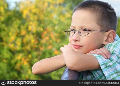 little boy is lean elbow on bridge fence and looking forward