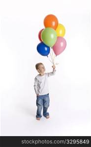 Little boy is looking at a bunch of colored balloons in his hand