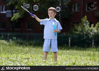 little boy is played with soap bubbles in the street